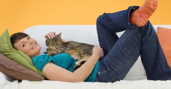 a cat-loving woman cuddles with her furry friend on her couch
