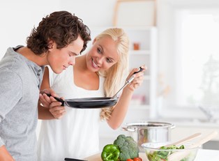 a young couple cooks together and tastes their masterful cuisine