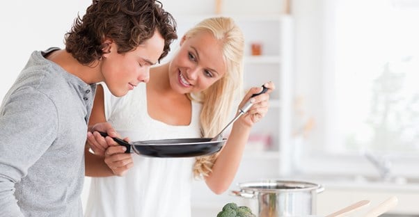 a young couple cooks together and tastes their masterful cuisine