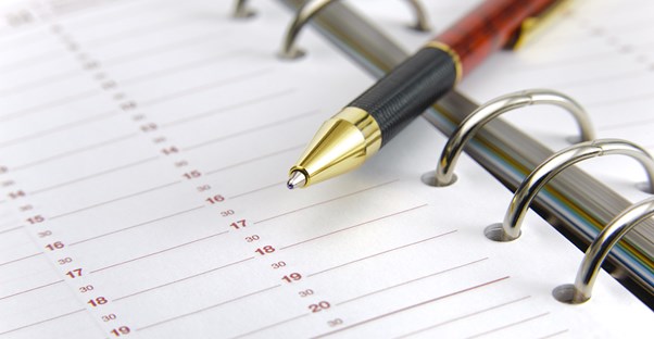 A red pen rests on a calendar