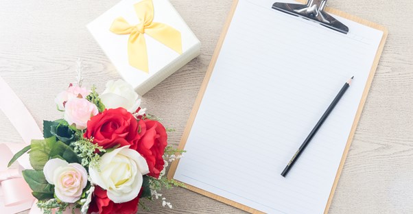 A checklist is set down next to a flower arrangement and a small gift