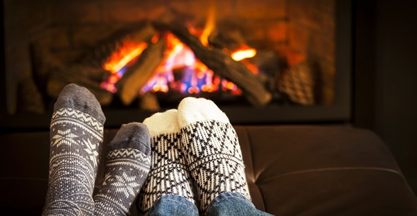 A couple warming their feet by a fire during their romantic staycation