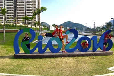 Olympic athletes pose on a Rio sign in the Olympic Village.