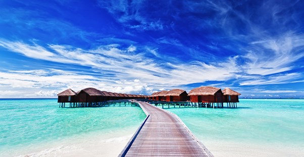 a boardwalk leading to bora bora resort huts located on stilts over the ocean waters