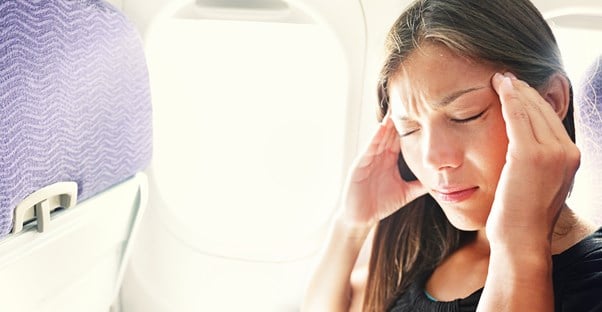 A woman massages her head while suffering from jet lag on her flight.