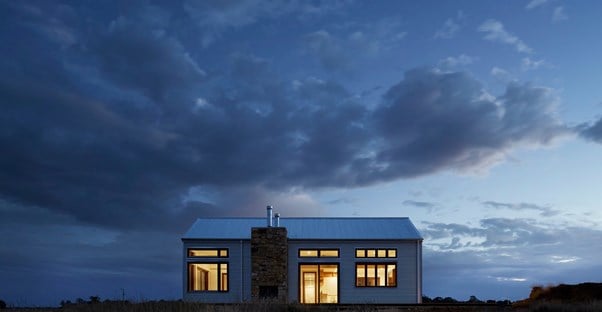 A solitary cabin is lit up at night in an expansive landscape.