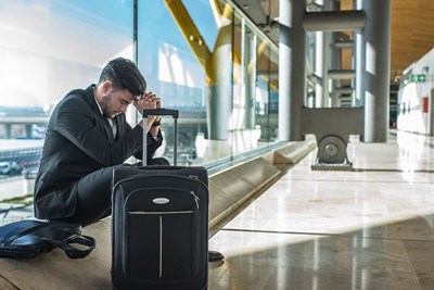 A man waits impatiently for his flight in an empty airport hallway