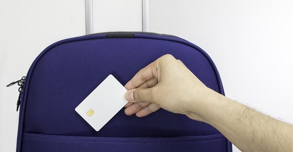 a hand placing a credit card into a suitcase