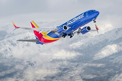 A Southwest Airlines plane taking off from Salt Lake City International Airport with snowy mountains in the background.