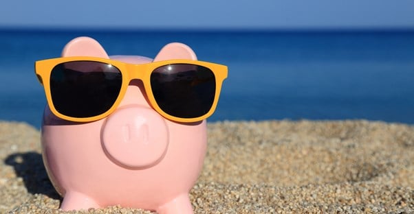a piggy bank with sunglasses on the beach