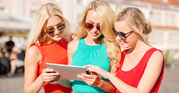 3 traveling women examine a map on a tablet