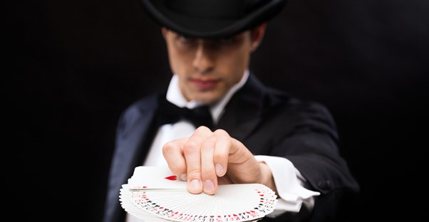 a magician holds a deck of cards out to the viewer