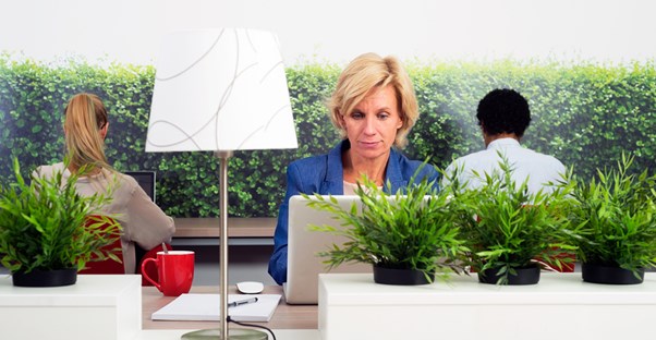 Woman works on her laptop surrounded by plants