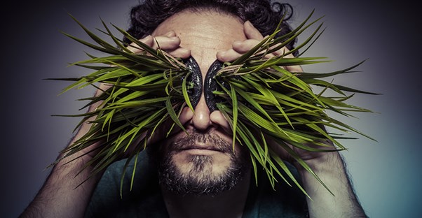 Man holding plants over his eyes. 