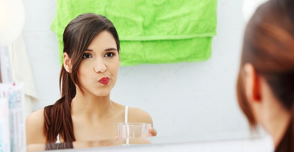 a woman using mouthwash