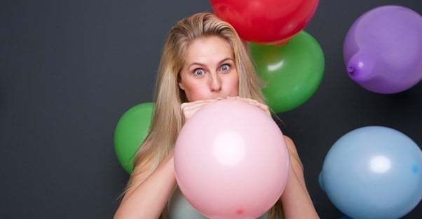 a woman blowing up a balloon
